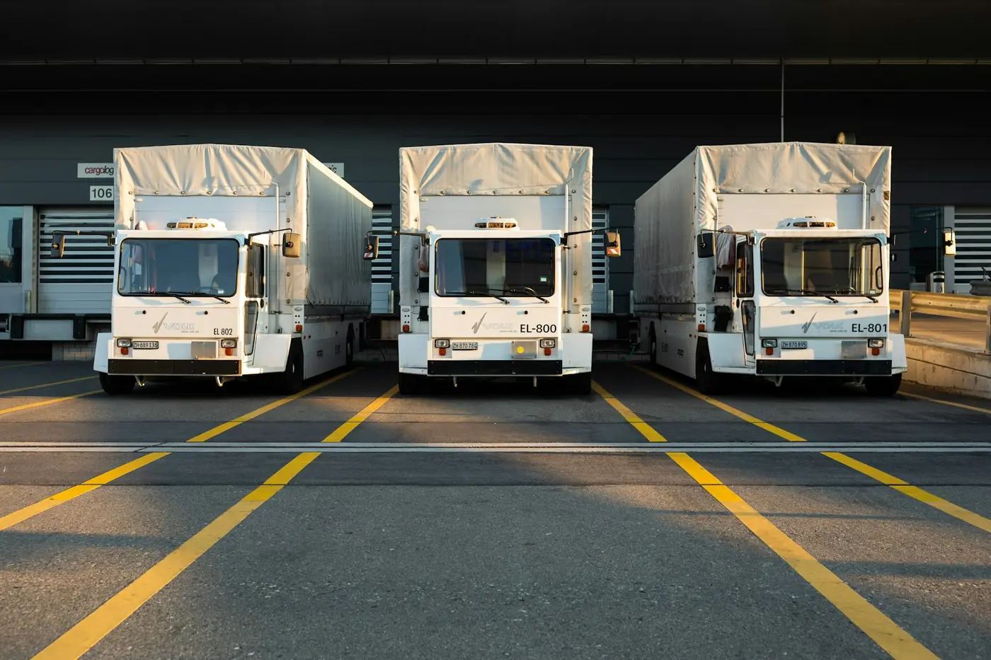Trois camions à quai devant un entrepôt